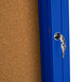 An Aarco blue metal indoor bulletin board cabinet with one corkboard door and a key in the lock.
