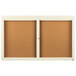 An Aarco ivory bulletin board cabinet with two cork boards behind glass doors.