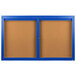 A blue framed bulletin board with two doors and a brown board.