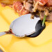 An Arcoroc stainless steel sauce spoon on a plate with food.