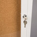 A key in a keyhole unlocking a white Aarco bulletin board cabinet.
