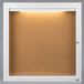 A white frame with a light on it enclosing a bulletin board.