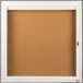 A white powder-coated Aarco indoor bulletin board cabinet with 1 door.