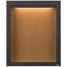A brown cork board cabinet with a light inside.