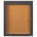 A brown Aarco bulletin board cabinet with a glass door and key lock.