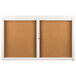 A brown rectangular bulletin board cabinet with two white doors with glass and a white border.