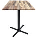 A square wood table with a black metal cross base.