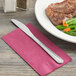 A Choice Milton stainless steel dinner knife on a napkin next to a plate of steak and vegetables.