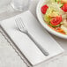 A Choice Windsor stainless steel salad fork on a white plate of salad.