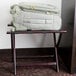A mahogany wood Lancaster Table & Seating folding luggage rack holding a suitcase.