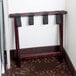 A Lancaster Table & Seating mahogany wood luggage rack with black straps.