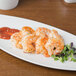 A Schonwald white porcelain long tray with shrimp and sauce.