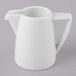 A Schonwald white porcelain creamer with a handle on a gray surface.
