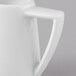 A close-up of a Schonwald white porcelain creamer with a handle.
