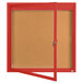 A red enclosed bulletin board with a cork board inside and a door with a lock.