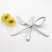 An Arcoroc stainless steel teaspoon with flowers on the handle.
