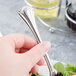 A hand holding a World Tableware stainless steel salad fork.