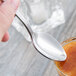 A Libbey stainless steel teaspoon being used to scoop food from a bowl.