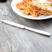 A plate of spaghetti and a Libbey Quantum stainless steel dinner knife on a table.