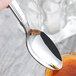 A Libbey stainless steel dessert spoon with sauce on it.