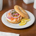 A bagel with salmon, onions, and lemon on a Schonwald Avanti Gusto porcelain plate.