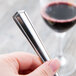 A person holding a Libbey stainless steel dessert fork next to a glass of wine.