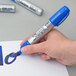 A person holding a blue Sharpie King Size marker and writing.