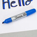 A close-up of a blue Sharpie marker writing the word "hello" on paper.