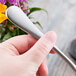 A hand holding a Master's Gauge stainless steel spoon.