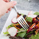 A Libbey stainless steel salad fork over a plate of vegetable salad