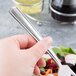 A hand holding a Libbey stainless steel salad fork over a salad