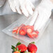 A person in gloves putting strawberries in a VacPak-It chamber vacuum packaging bag.