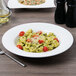 A Villeroy & Boch white porcelain bowl filled with pasta, tomatoes, and cheese.