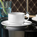 A Villeroy & Boch white porcelain saucer with a white cup on a black surface.