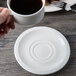 A hand holding a Villeroy & Boch white porcelain saucer with a cup of coffee on it.