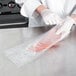 A person wearing white gloves using a VacPak-It chamber vacuum packaging pouch to pack meat.