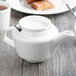 A white Villeroy & Boch porcelain teapot on a wood surface.