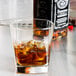 A Libbey double old fashioned glass filled with amber liquid and ice on a table with a bottle of Jack Daniels.