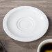 A white Villeroy & Boch porcelain saucer on a wood surface.