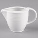 A close-up of a Villeroy & Boch white porcelain creamer with a handle.