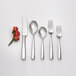 An Arcoroc stainless steel dinner fork on a table with a white rose.
