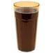 A Cambro Newport amber plastic tumbler filled with dark liquid with a yellow rim.
