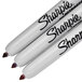 A set of three white Sharpie fine point permanent markers with black writing.
