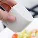 A hand holding a white Villeroy & Boch salt and pepper shaker cube.