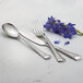 Arcoroc stainless steel dinner fork with a flower on a table.