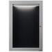 A black and white rectangular Aarco message center with a light on the door.