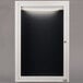 A white rectangular door with a black letter board inside.