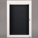 A white frame with a black letter board behind a windowed door.