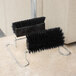 A pair of Carlisle Spectrum black boot and shoe brushes on a stand.