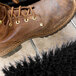 A brown boot with laces using a Carlisle black boot and shoe brush.